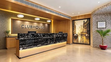 Un comptoir d’accueil avec une enseigne indiquant « CLUBHOUSE », un lambris en bois et une vue sur le paysage urbain.