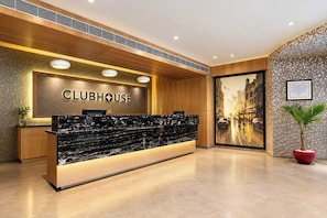 A reception desk with a 'CLUBHOUSE' sign, wooden paneling, and a cityscape view. - Clubhouse Hotel by CheckIn Kolkata (Kolkata)