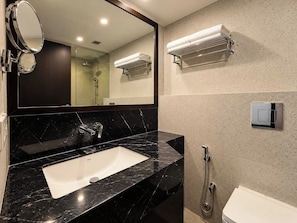 A modern bathroom with a black marble sink, a large mirror, a towel rack, and a shower. - Clubhouse Hotel by CheckIn Kolkata (Kolkata)