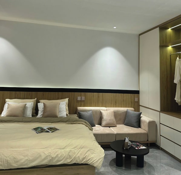 A modern bedroom with a large bed, a sofa, a coffee table, and a wardrobe.
