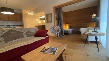Een woonkamer met een rode bank, een houten salontafel en een eethoek met een ronde tafel en stoelen.