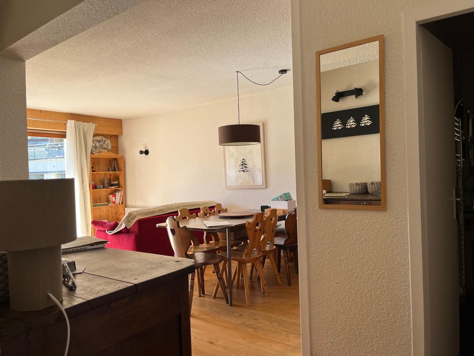 Un'area pranzo con un tavolo e sedie in legno, un lampadario e una libreria sullo sfondo.