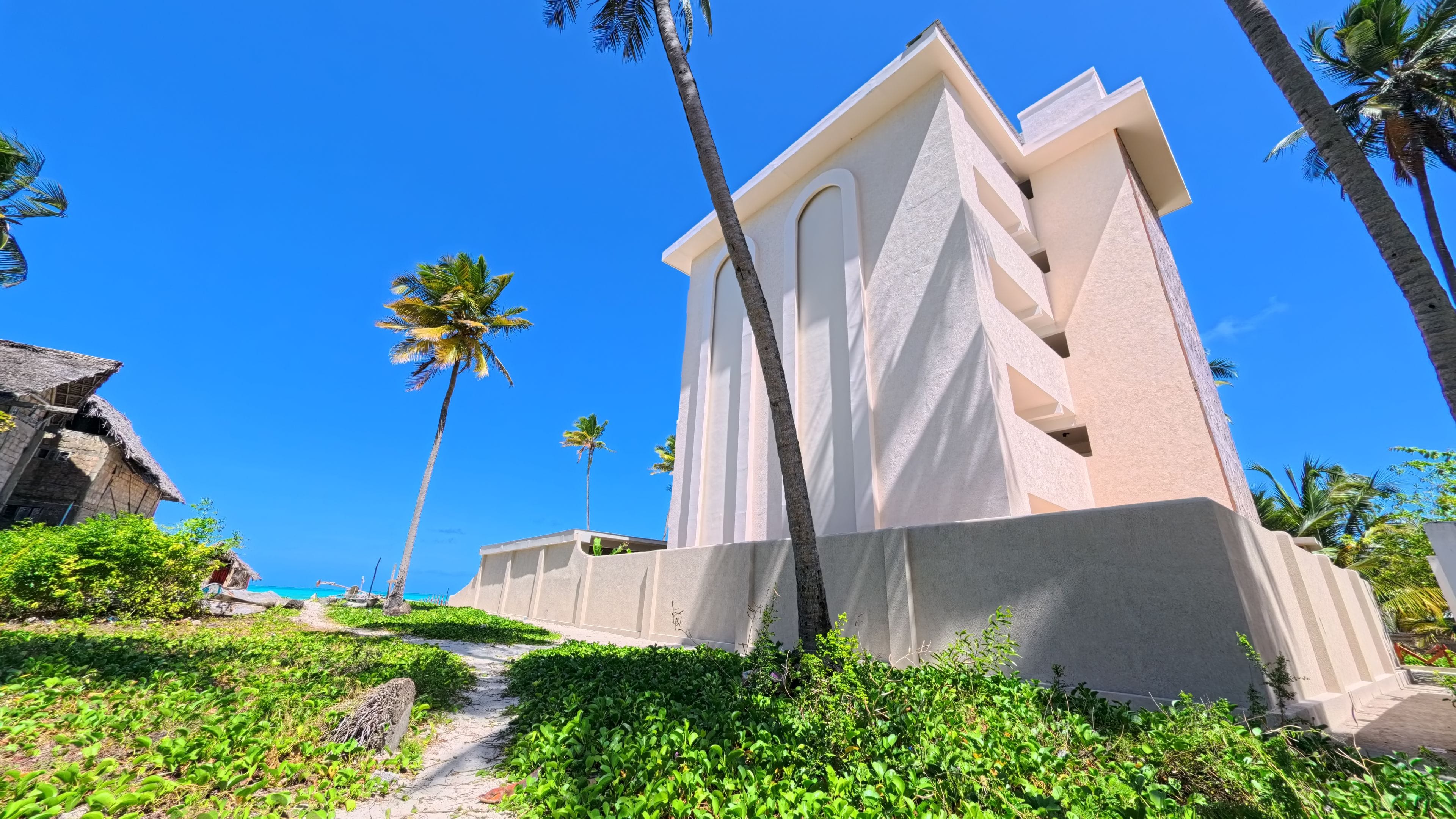 A modern building with a unique architectural design, surrounded by lush greenery and palm trees.