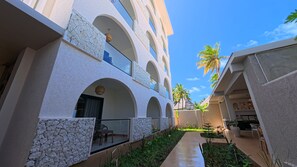 A hotel with multiple balconies, a central pathway, and tropical vegetation.