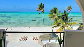 Un balcon avec vue sur une plage, des palmiers et l’océan.