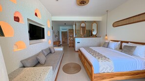 A modern bedroom with a bed, seating area, and a TV mounted on the wall.