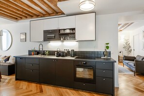 Una cocina moderna con una isla central, electrodomésticos integrados y techo de madera.