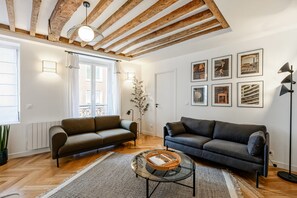 Una sala de estar moderna con dos sofás, una mesa de centro de vidrio y un ventanal grande.