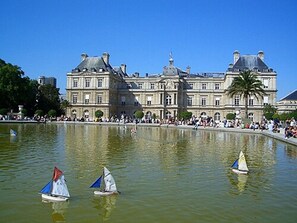 Un edificio histórico grande con una fuente de agua reflectante en primer plano.