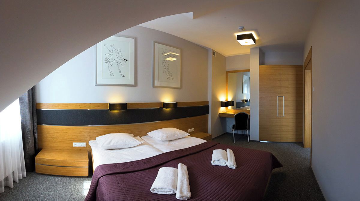 Une chambre d’hôtel avec un grand lit, un bureau et une armoire.