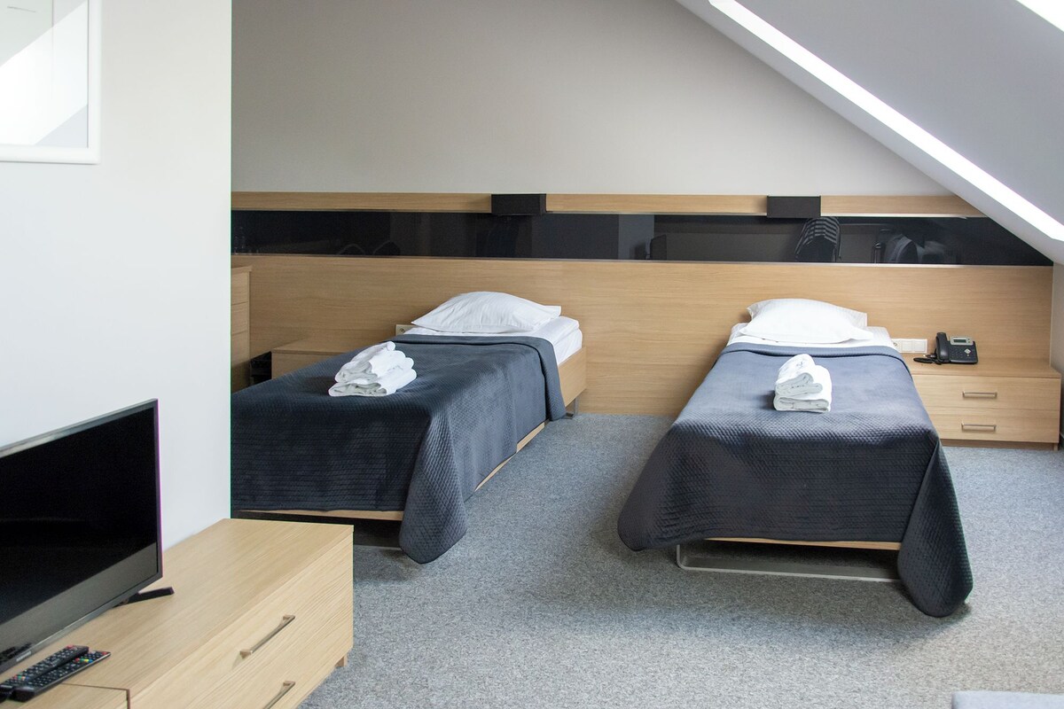 A hotel room with two beds, a desk, a TV, and a phone on the desk.