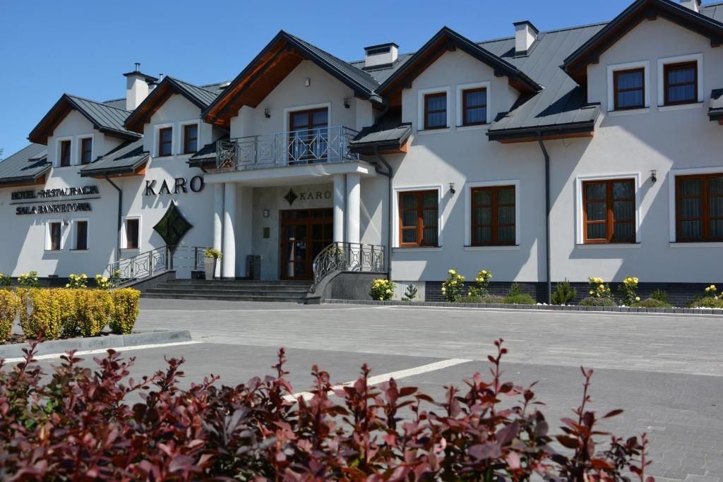 Um hotel com entrada destacada, varanda e uma placa com a inscrição 'KARO'.