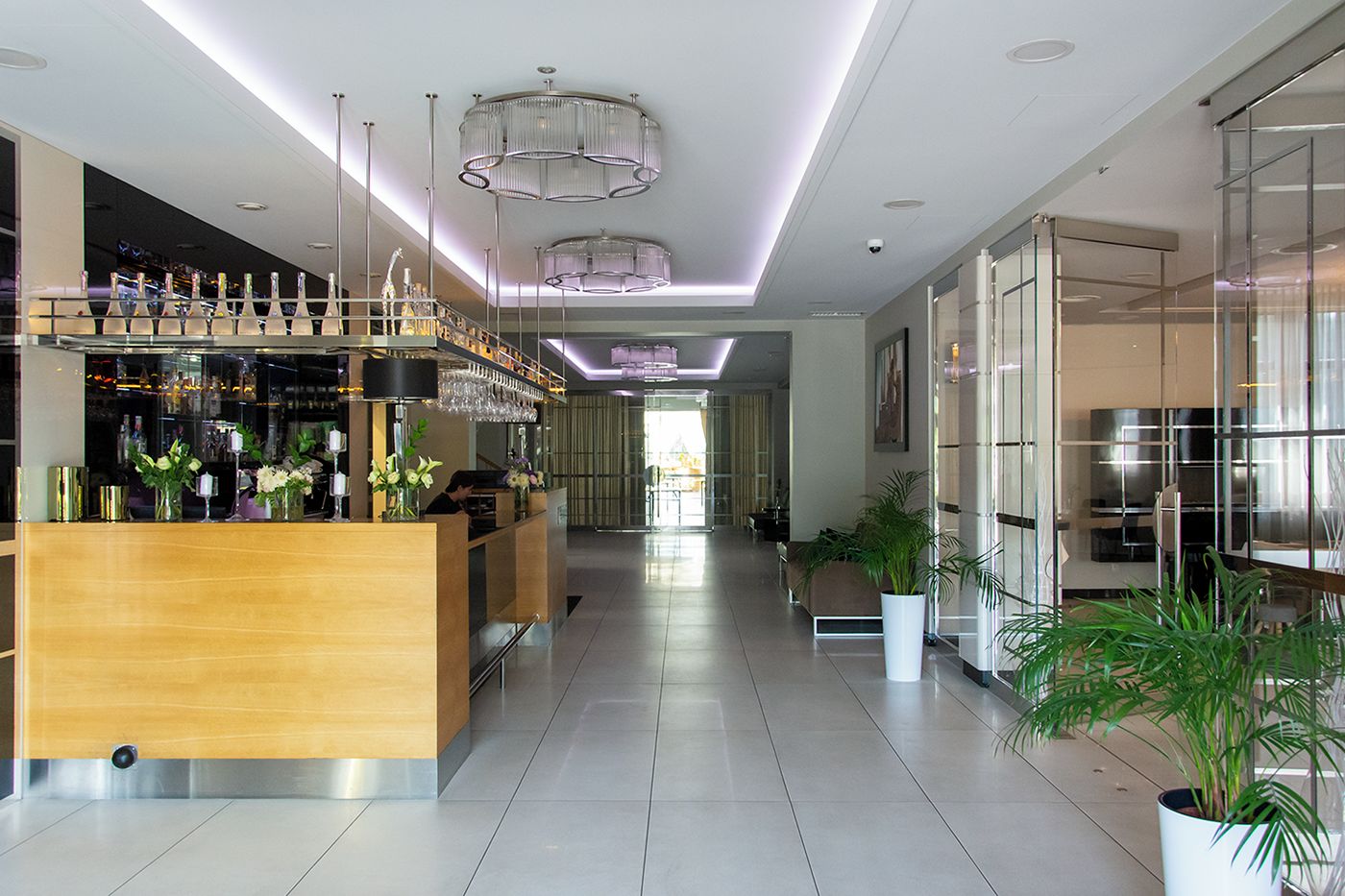 Eine moderne Bar mit Holztresen, Barhocker und einer Auswahl an Flaschen und Gläsern.
