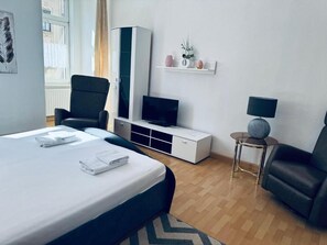 Ein modernes Hotelzimmer mit Bett, Fernseher, Schreibtisch und Stuhl.