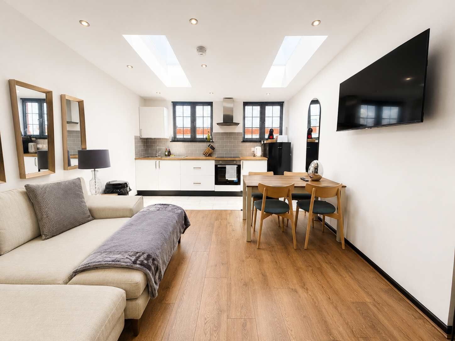 A modern apartment with a living area, kitchenette, and dining space.