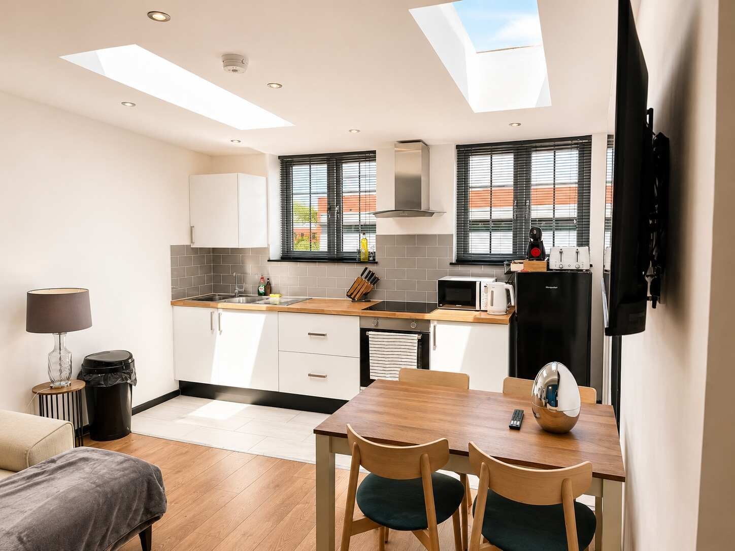 A modern kitchen with skylights, a dining area, and a living space.