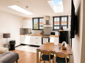 A modern kitchen with skylights, a dining area, and a living space. - Modern 2 Bed Flat in Heart of Warrington City (Warrington)