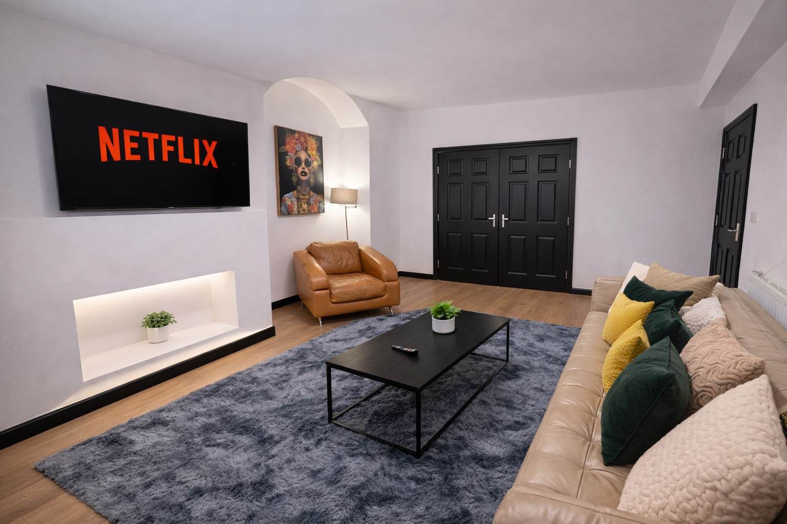 Un salon comprenant un canapé, un fauteuil, une table basse, un téléviseur et une porte.