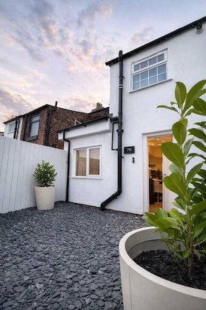 A residential property with a white exterior, a black gutter, a potted plant, and a gravel driveway. - Modern house-4 Bed - Close to Motorway & Town, (Warrington)