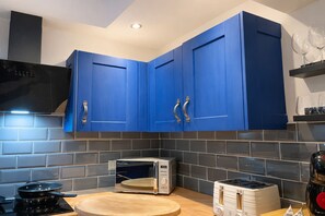 A kitchen with blue cabinets, a microwave, a toaster, and a stove. - Modern house-4 Bed - Close to Motorway & Town, (Warrington)