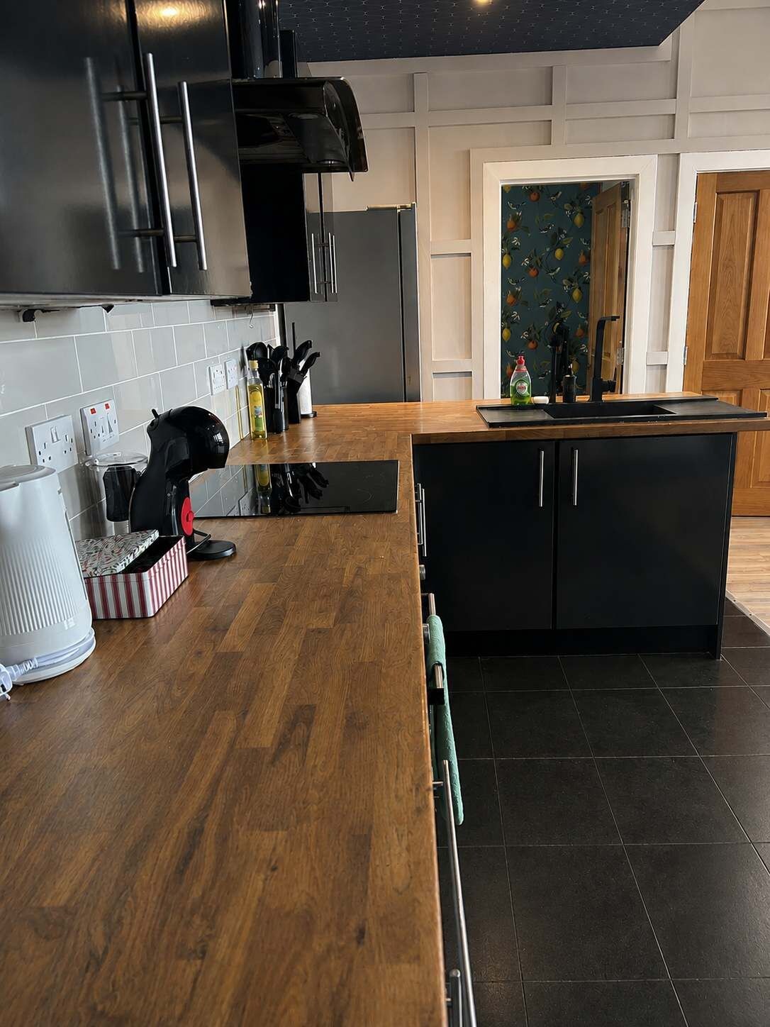 A modern kitchen with a wooden countertop, black cabinetry, and a built-in island.