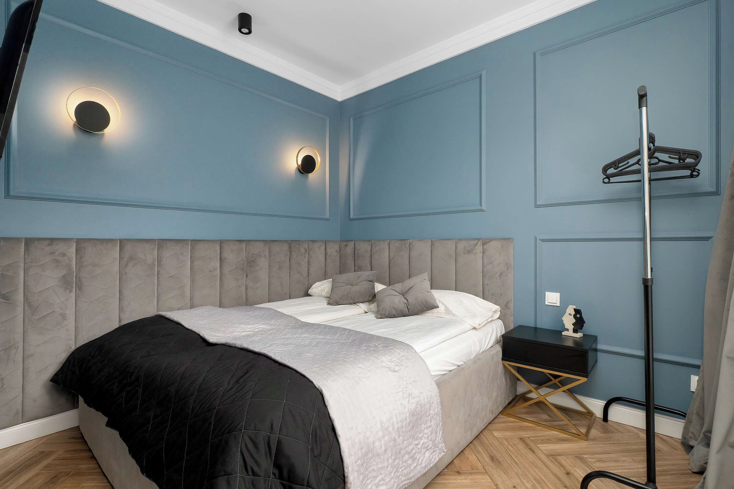 A bedroom with a bed, bedside table, and a floor lamp.