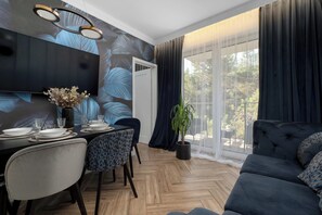 Uma zona de refeições moderna com uma mesa posta para quatro pessoas, um sofá e uma janela grande com cortinas.