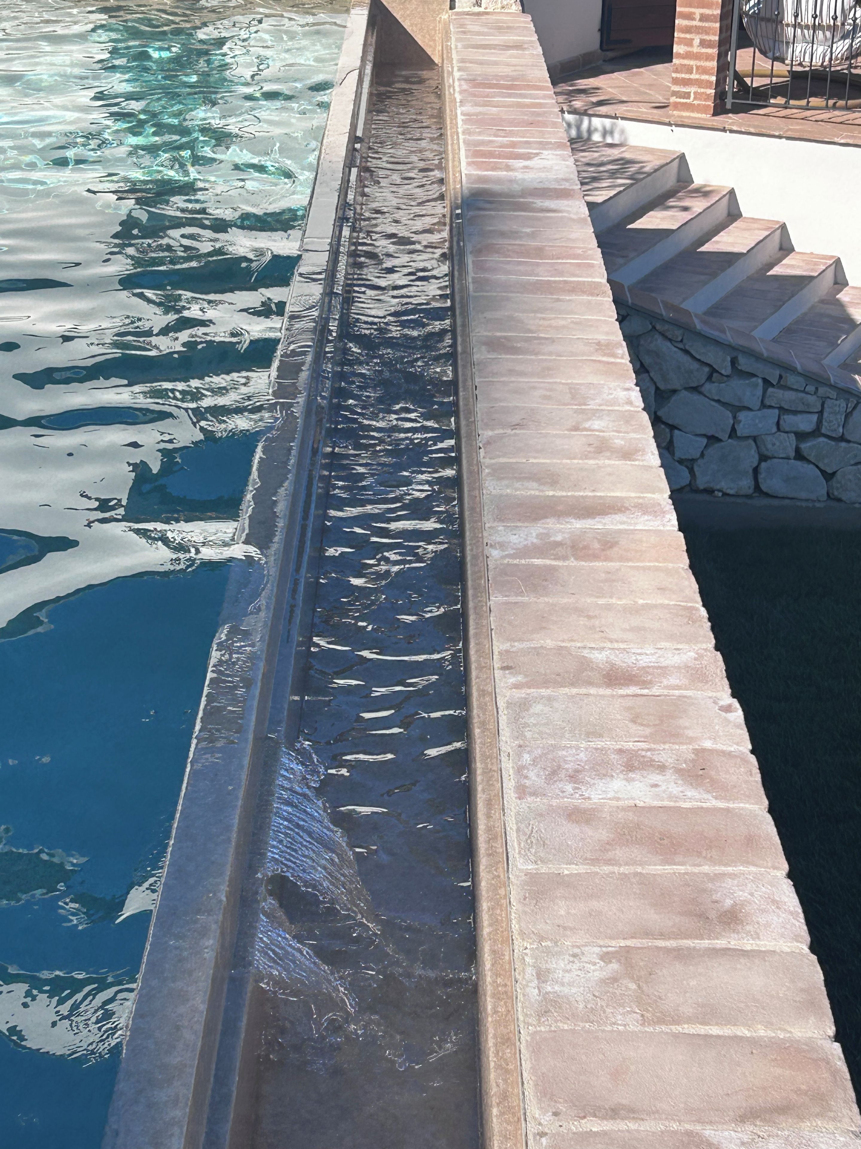 Una piscina con borde de piedra y escalones que bajan al agua.