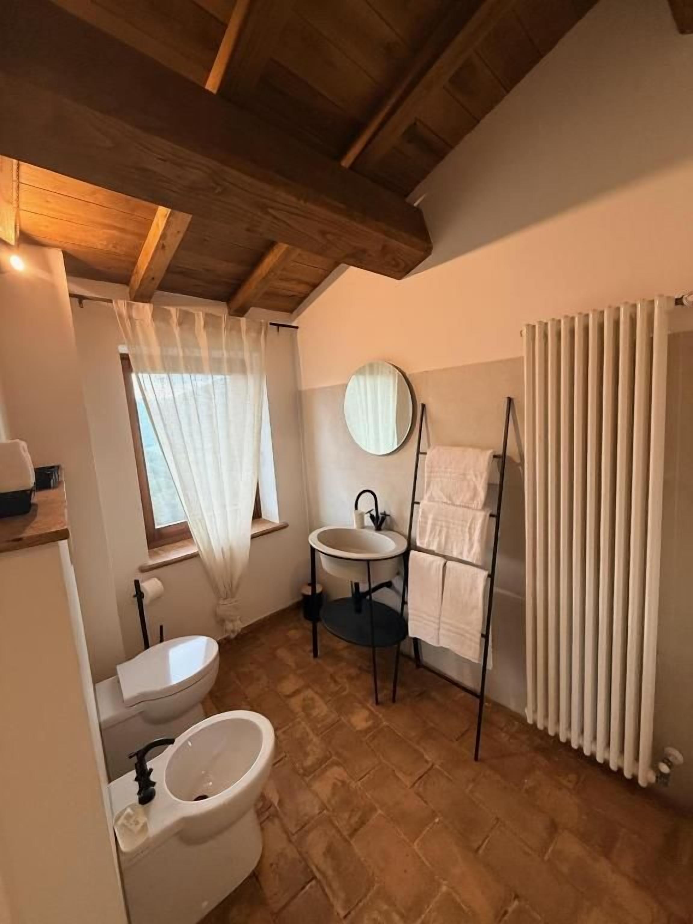Een badkamer met toilet, bidet, wastafel en een handdoekhouder.
