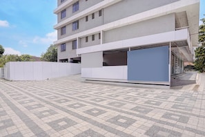 Un edificio moderno con fachada plana, varios ventanales y un área exterior cubierta con suelo estampado.