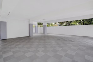 Un interior espacioso con piso de cuadros, paredes blancas y vistas al exterior con vegetación.