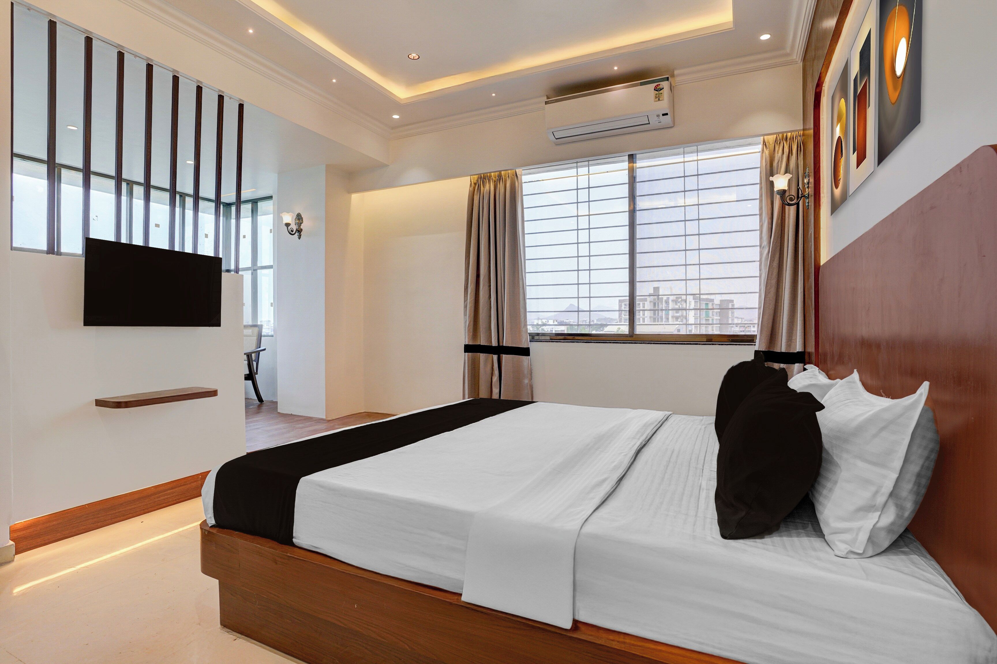 Una habitación de hotel moderna con una cama grande, un televisor de pantalla plana en la pared y una ventana con cortinas.
