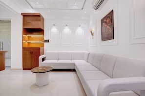 A modern interior with a white sofa, a wooden cabinet, and a round table with a magazine.