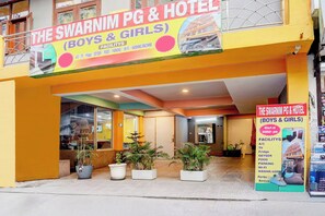 A hotel named 'The Swarnim PG & Hotel' with a signboard listing amenities like A/C, TV, fridge, geyser, food, parking, Wi-Fi, and washing machine. - Hotel O The Swarnim (Noida)
