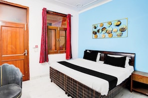 Une chambre à coucher avec un lit, une chaise, une fenêtre avec des rideaux et un élément de décoration murale.