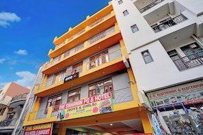 A multi-story hotel with balconies, a PG & Hotel & Banquet sign, and a visible shop on the ground floor. - Hotel O The Swarnim (Noida)