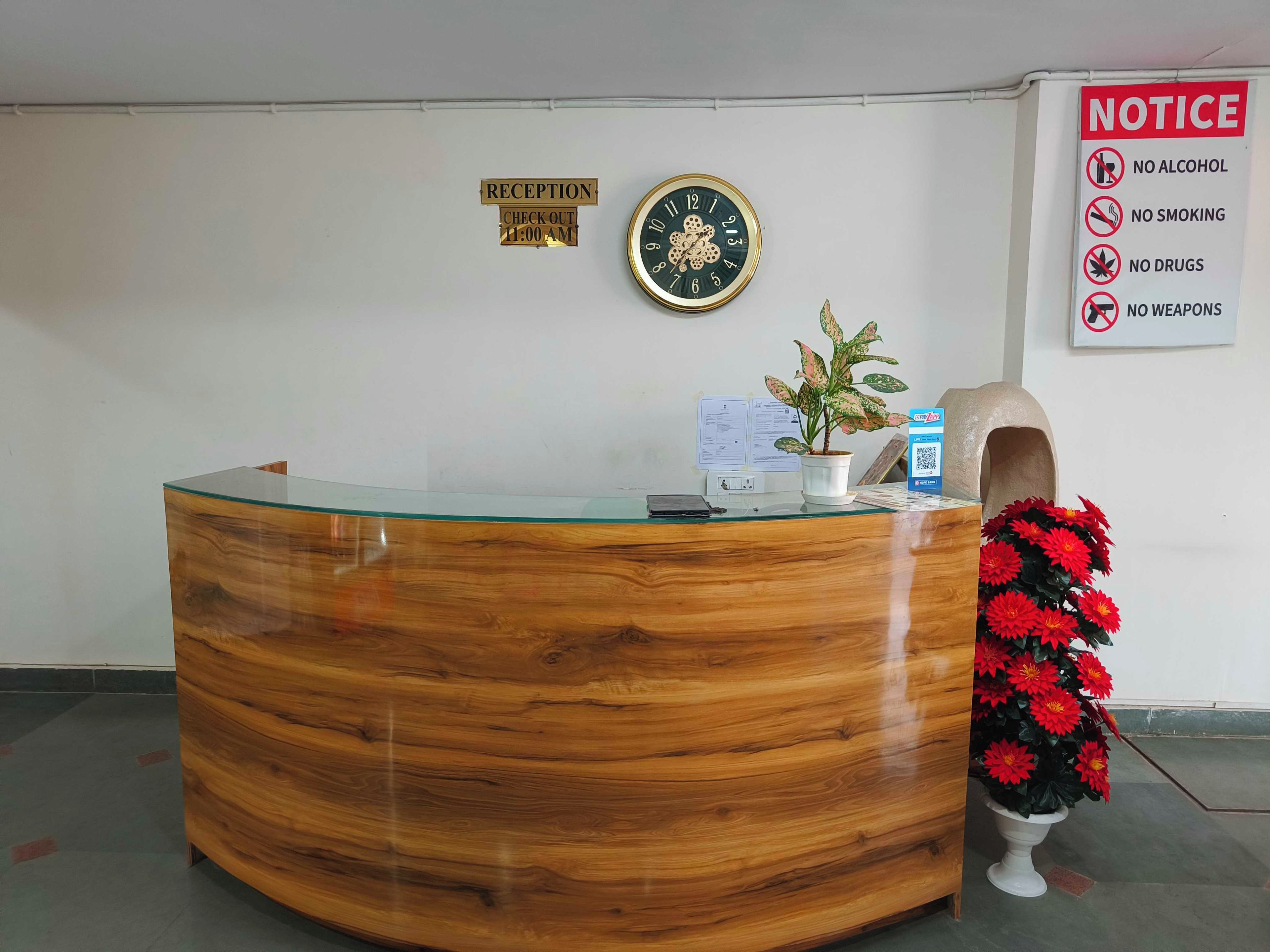 A reception desk with a clock, a notice board, and a potted plant.