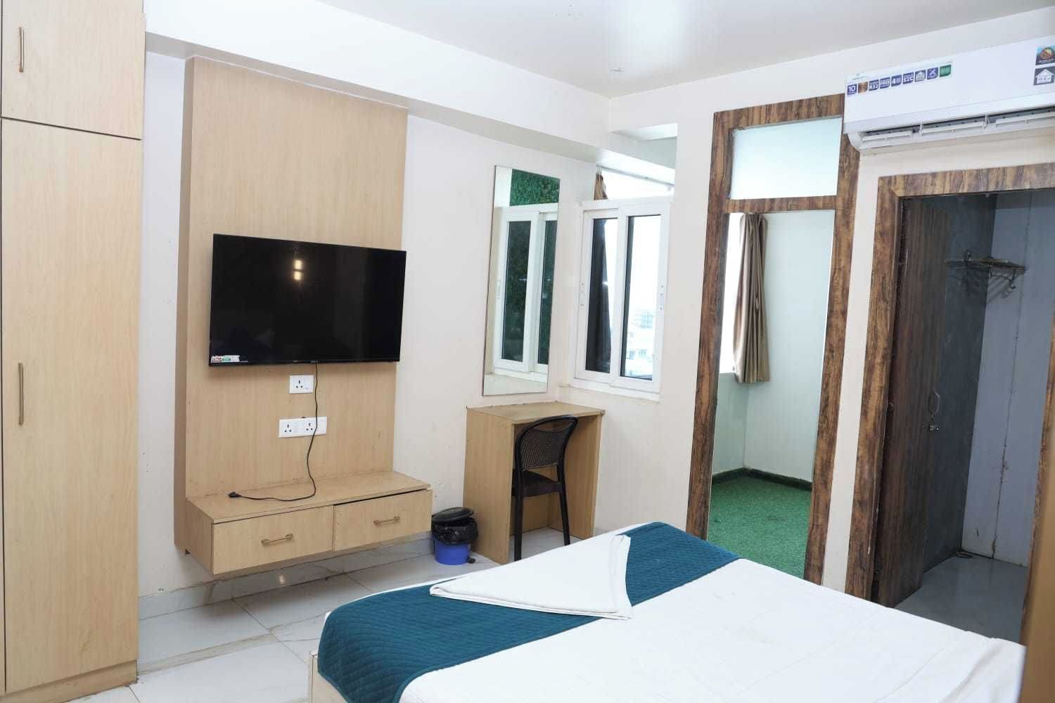 A hotel room with a bed, a desk, a television, and a wardrobe.