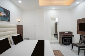 A hotel room with a bed, a desk, a chair, a mirror, and a television.