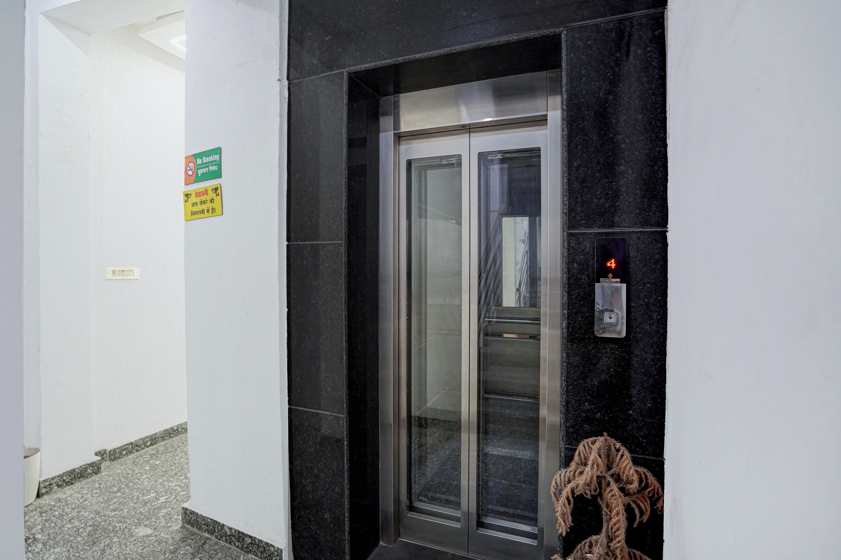Un ascensor con pantalla digital y un letrero de prohibido fumar en la pared.