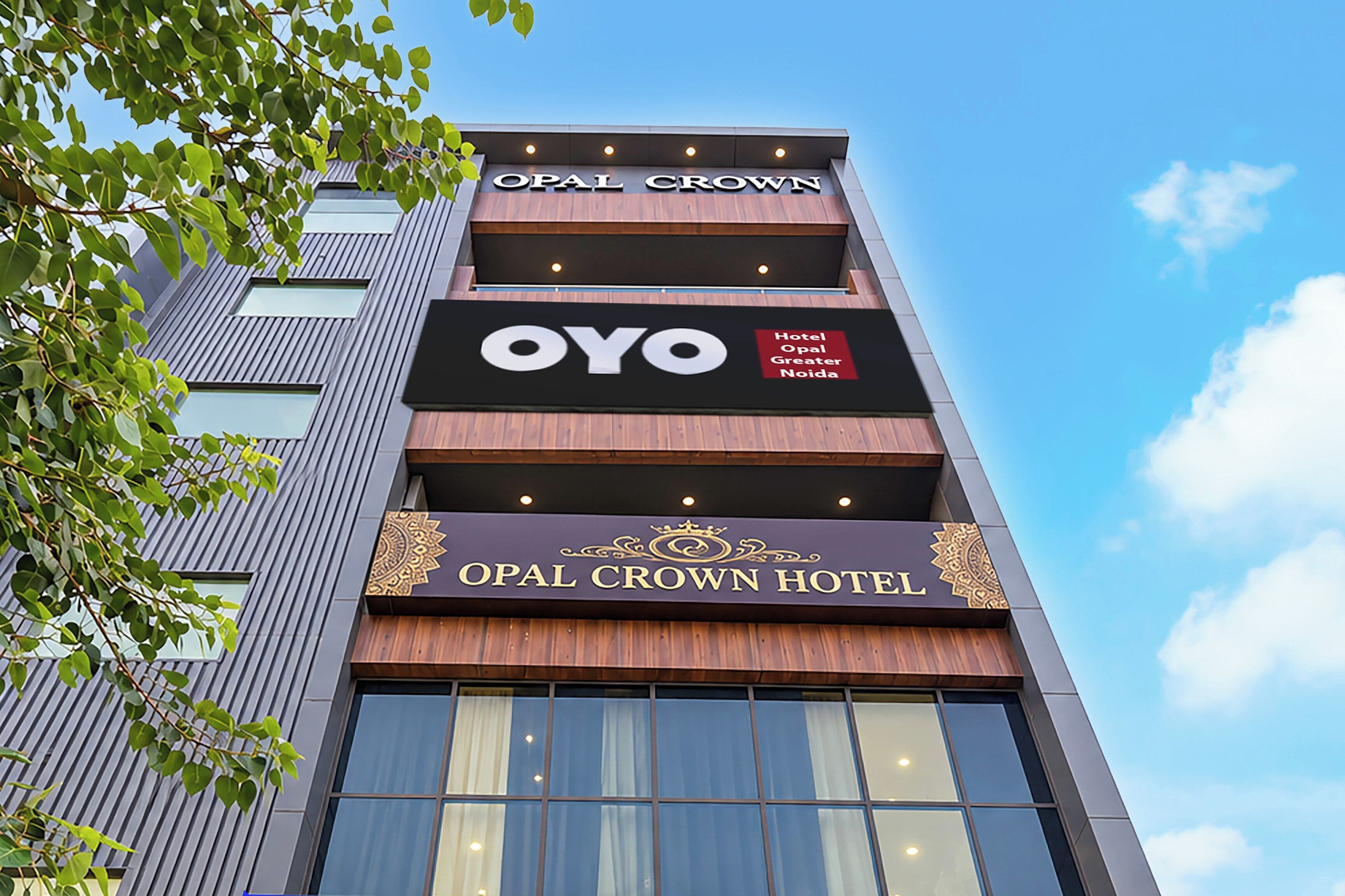 Um edifício de hotel com placas indicando 'OPAL CROWN HOTEL' e 'OYO Hotel Opal Greater Noida'.