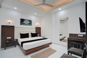 Une chambre moderne avec un grand lit, des tables de chevet, un ventilateur de plafond, un éclairage encastré, un climatiseur mural et un miroir.