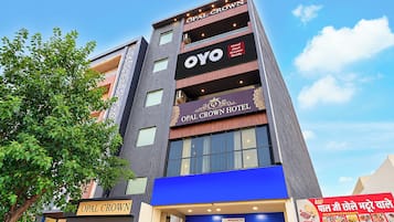 Un hotel de varios pisos con señalización que indica 'OPAL CROWN HOTEL' y 'OPAL CROWN Hotel Opal Greater Noida'.