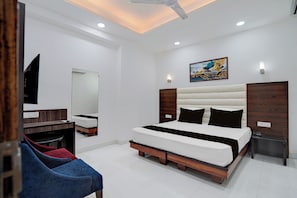 Une chambre moderne avec un grand lit, un bureau, une chaise et un ventilateur de plafond.