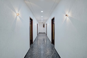 A corridor with white walls, dark floor, and doors with wooden frames.