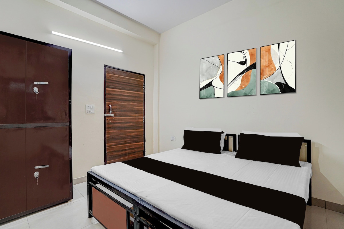 A hotel room with a bed, a wardrobe, and abstract wall art.