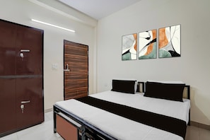 A hotel room with a bed, a wardrobe, and abstract wall art. - Hotel O Prime Stay (Noida)