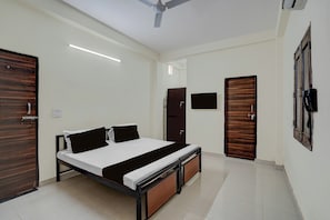 A bedroom with a bed, a wardrobe, a television, and a ceiling fan. - Hotel O Prime Stay (Noida)