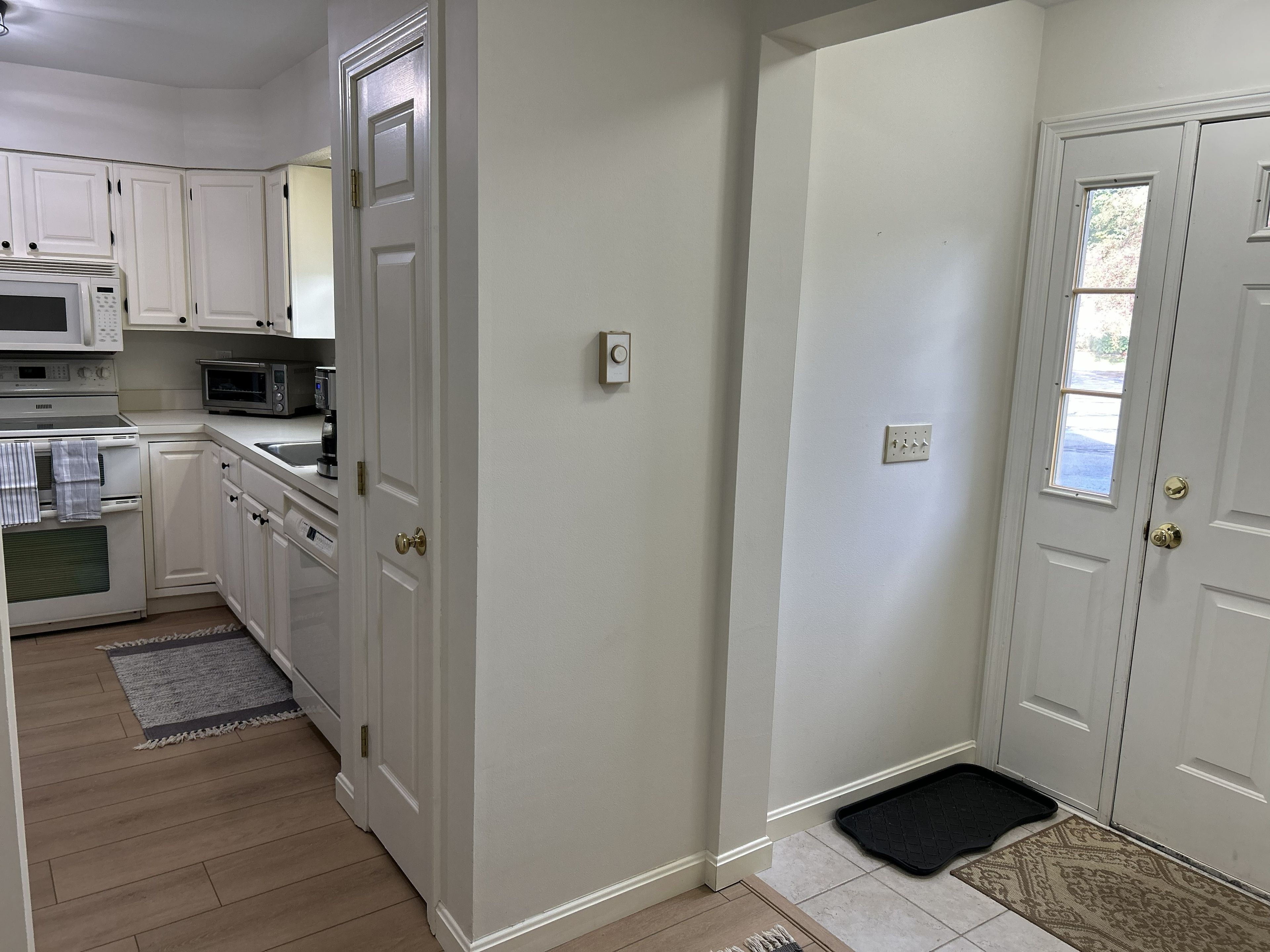A kitchen with white cabinets, a microwave, an oven, and a sink.