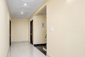 Un pasillo con piso de color claro, una puerta al final y un enchufe en la pared.
